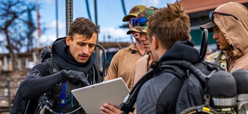 Sailors assigned to Mobile Diving and Salvage Unit One (MDSU-1) discuss search and survey operations in Lahaina Harbor in Maui, Aug. 27, 2023.