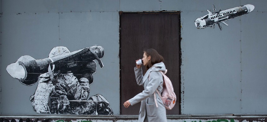  in this 2022 photo, a woman passes by graffiti depicting a Ukrainian serviceman shooting a US-made Javelin portable anti-tank missile system in central Kyiv. 