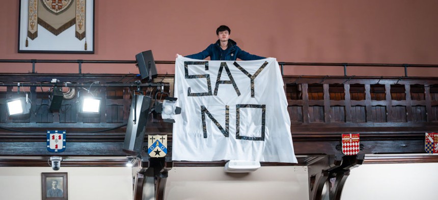 A protestor holds up a banner during Sam Altman's visit to The Cambridge Union to receive the Professor Hawking Fellowship on behalf of OpenAI on November 1, 2023, in Cambridge, England.
