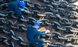 Navy Seamen Kevoy Gordon, left, and Andrew Crickard sand and prepare the USS Tripoli’s anchor chain for painting during a maintenance availability in San Diego, April 20, 2023.