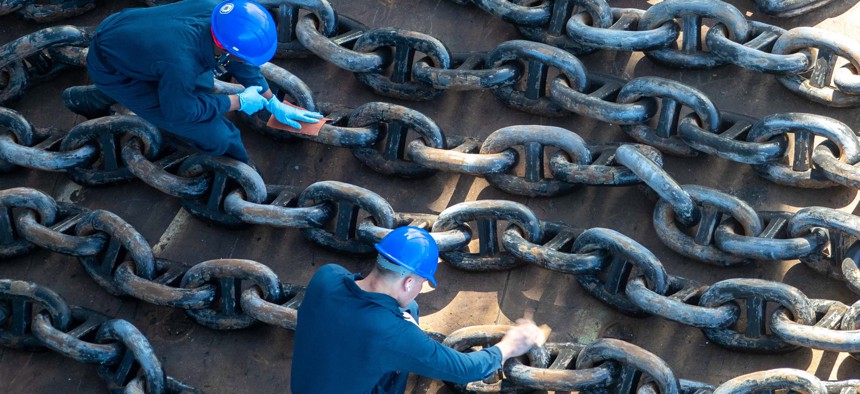 Navy Seamen Kevoy Gordon, left, and Andrew Crickard sand and prepare the USS Tripoli’s anchor chain for painting during a maintenance availability in San Diego, April 20, 2023.