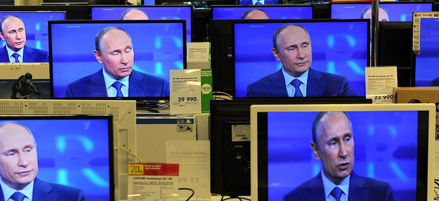 A customer walks past the TV screens in a shop in Moscow, on April 25, 2013, during the broadcast of President Vladimir Putin's televised question and answer session with the nation.