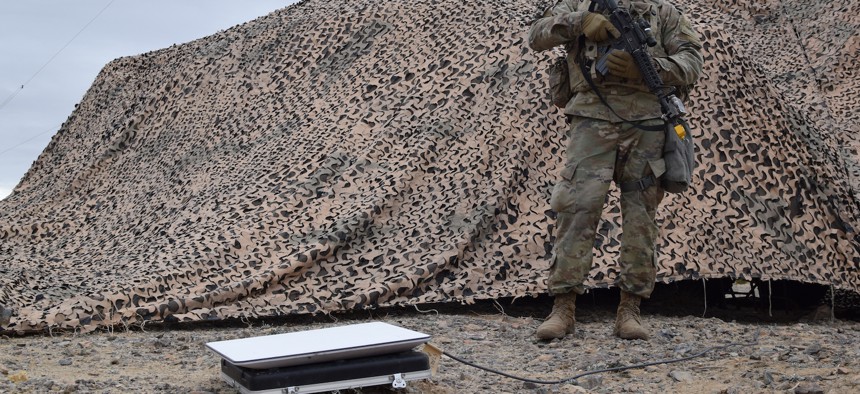 A soldier stands near a Starlink device at the National Training Center at Fort Irwin, California. 