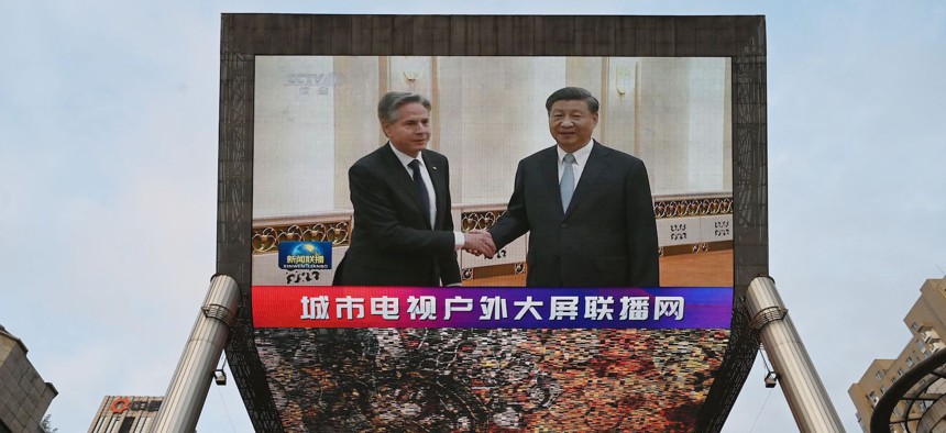 A China Central Television news broadcast shows footage of US Secretary of State Antony Blinken (L) meeting with China's President Xi Jinping, on a giant screen outside a shopping mall in Beijing on June 19, 2023.