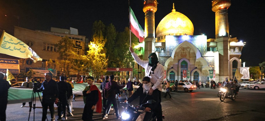 Demonstrators wave Iran's flag as they gather at Palestine Square in Tehran on April 14, 2024, after Iran launched a drone and missile attack on Israel. 