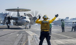 Navy Petty Officer 2nd Class Brandon Frayde guides an E-2C Hawkeye, attached to the "Screwtops" of Airborne Command and Control Squadron 123, during flight operations aboard the aircraft carrier USS Dwight D. Eisenhower in the Red Sea, Nov. 5, 2023. 