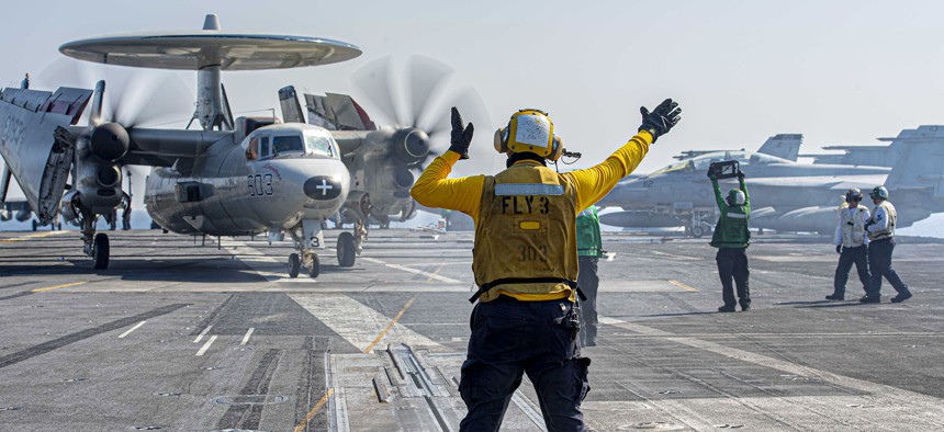 Navy Petty Officer 2nd Class Brandon Frayde guides an E-2C Hawkeye, attached to the "Screwtops" of Airborne Command and Control Squadron 123, during flight operations aboard the aircraft carrier USS Dwight D. Eisenhower in the Red Sea, Nov. 5, 2023. 