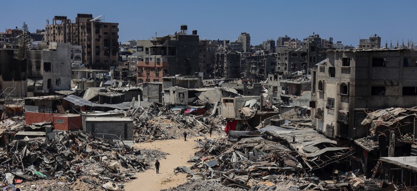 People walk on a street next to buildings destroyed during Israeli bombardment at the Jabalia camp for Palestinian refugees in the northern Gaza Strip on July 23, 2024.