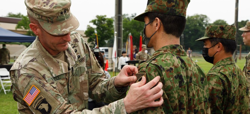 Maj. Gen. JB Vowell, left, commander of U.S. Army Japan, places a new patch on a Japan Ground Self-Defense Force member during a ceremony at Camp Zama, Japan, June 17, 2022.