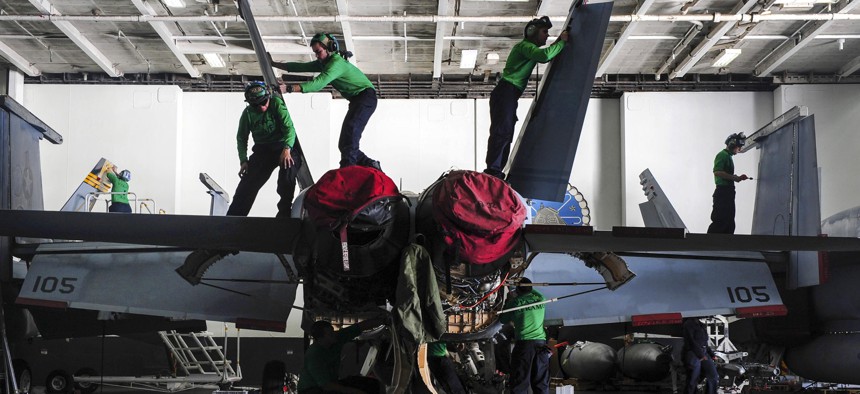 Sailors of Strike Fighter Squadron 32 maintain an F/A-18F Super Hornet in the hangar bay of the aircraft carrier Dwight D. Eisenhower.