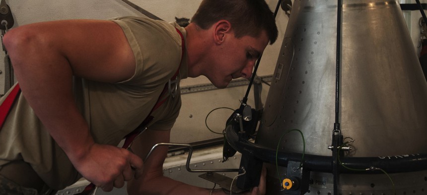 A maintainer with the Air Force's 90th Missile Maintenance Squadron removes the screws holding the nose point of a Minuteman III ICBM at F.E. Warren Air Force Base, Wyoming, in 2016. 