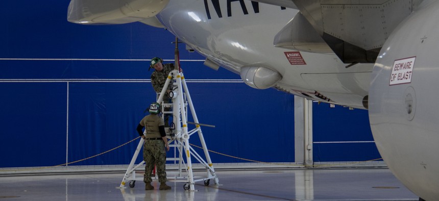 Aviation Structural Mechanic (Hydraulics) 1st Class Ryan Theobald, right, and Aviation Electrician's Mate 3rd Class Ian Cervantes prepare a P-8A Poseidon to be lifted in a hangar on NAS Whidbey Island during routine maintenance, November 13, 2023. 