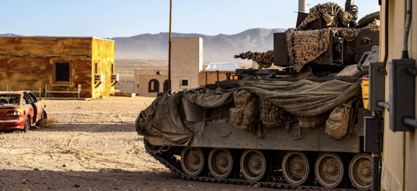 Soldiers with the 1st Armored Brigade Combat Team, 3rd Infantry Division, scan a simulated village with a Bradley Fighting Vehicle at the National Training Center, Fort Irwin, California, July 21, 2024.