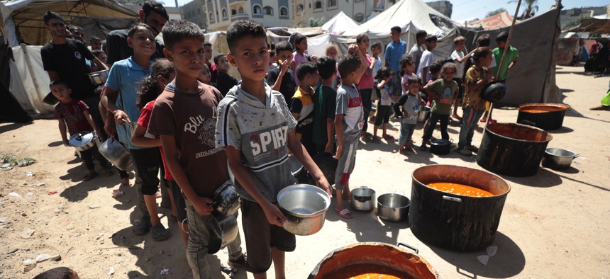 Forcibly displaced Palestinian children holding empty pots line up to receive food distributed a charity organization as Israeli attacks and blockade of aids continue in Zawayda, Gaza, on September 11, 2024.