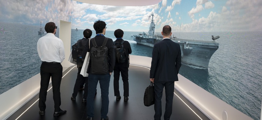 Visitors watch a video loop at the RTX exhibition stand at the Farnborough International Airshow on July 22, 2024, at Farnborough, England. 