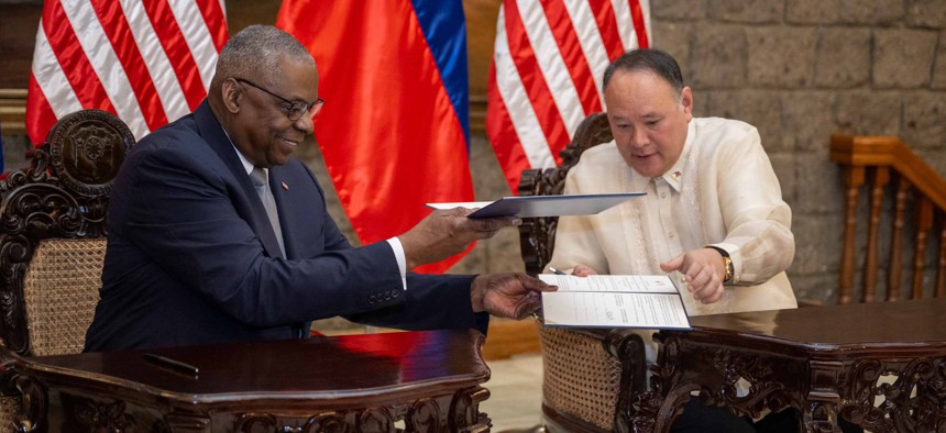 Secretary of Defense Lloyd Austin and Philippine Defense Secretary Gilbert Teodoro exchange documents while signing the General Security of Military Information Agreement at Camp Aguinaldo in Manila, Philippines, Nov. 18, 2024.