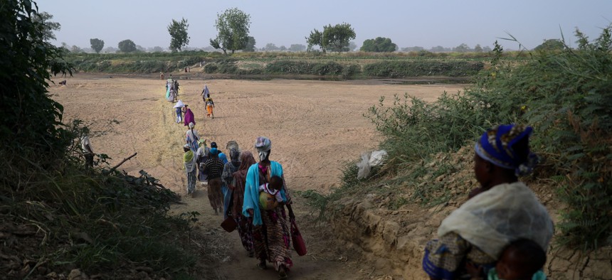 In this 2022 photo, women cross the dry bed of the White Volta river to their farms in Burkina Faso from northern Ghana.