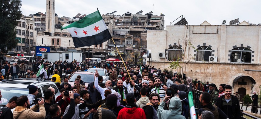 Residents of Hama, Syria, wave the rebel coalition's flag as they demonstrate in support of the fight against the Assad regime on December 7, 2024.