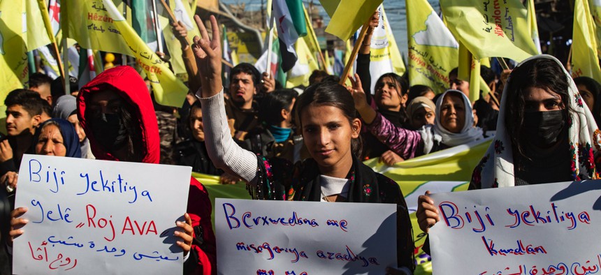 Syrian Kurds wave independence-era flags and flash the V for victory sign during a demonstration in support of the US-backed, Kurdish-led Syrian Democratic Forces in the northeastern city of Qamishli, on December 19, 2024.