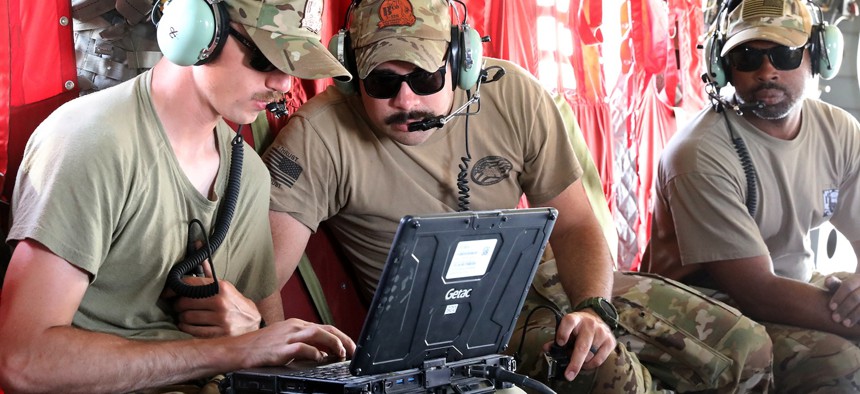 In this 2023 photo, Spc. Kalbi Wells, Staff Sgt. Chris Santiago and Sgt. Rickman Riley update maintenance records after performing an engine wash on a CH-47 Chinook helicopter at Camp Buehring, Kuwait. 