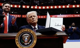 U.S. President Donald Trump holds up an executive order after signing it during an indoor inauguration parade at Capital One Arena on January 20, 2025.