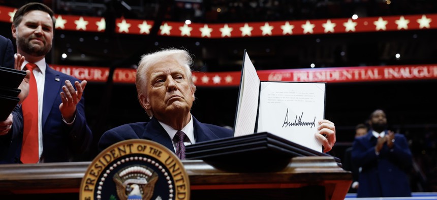 U.S. President Donald Trump holds up an executive order after signing it during an indoor inauguration parade at Capital One Arena on January 20, 2025.