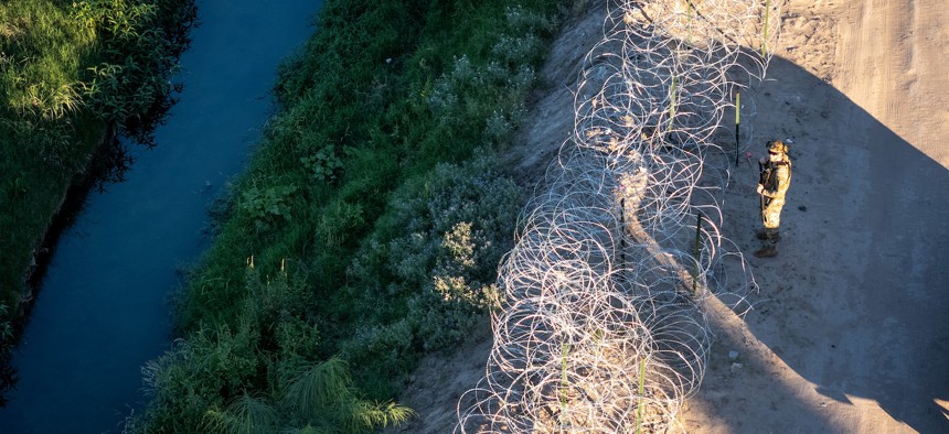 A Texas National Guard soldier inspects razor wire along the bank of the Rio Grande at the U.S.-Mexico border on September 18, 2024, in El Paso, Texas. 