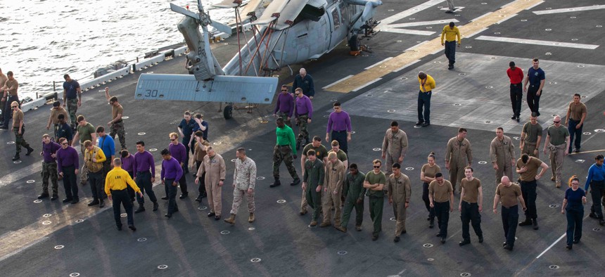 Sailors and Marines aboard the amphibious assault ship USS Bataan (LHD 5) do a FOD walkdown as the ship sails through the Strait of Bab-Al-Mandeb in June 2020.