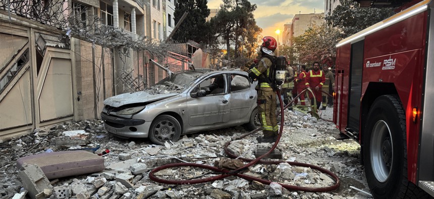 Iranian first responders gather outside a building that was hit by an Israeli strike in Tehran on June 13, 2025.