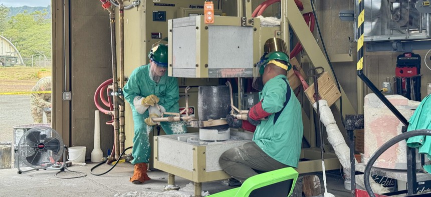 Marines Sgt. Jackson Glassel (left) and Cpl. Garrett Boyer move a container of molten metal to pour it into a mold at The Forge, at Schofield Barracks, Hawaii.