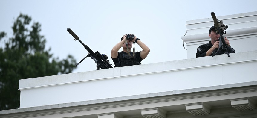 Members of the Secret Service's counter sniper team look out from the roof of the West Wing of the White House on August 5, 2025.