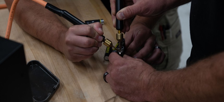 Joshua Turnbull, right, and Austin Wilt, 436th Maintenance Squadron avionics technicians, solders batteries together with nickel strips at the Air Force Repair Enhancement Program shop on Dover Air Force Base, Delaware, July 16, 2025.