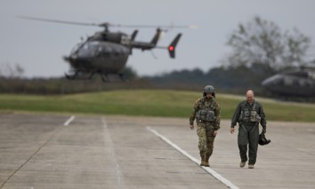 An instructor pilot and a student walk off a flight line at Fort Rucker, Alabama, after completing a flight in a UH-72 Lakota.