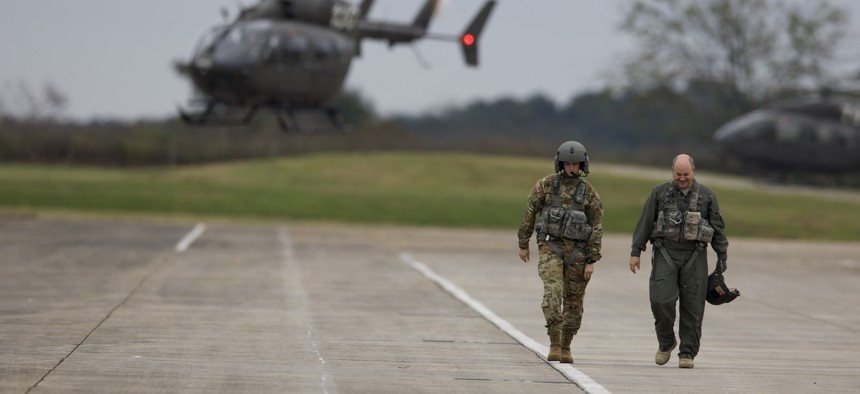 An instructor pilot and a student walk off a flight line at Fort Rucker, Alabama, after completing a flight in a UH-72 Lakota.