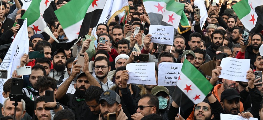 People hold flags and placards in Damascus as they celebrate the fall of Syria's president Bashar al-Assad. November 28, 2025. 