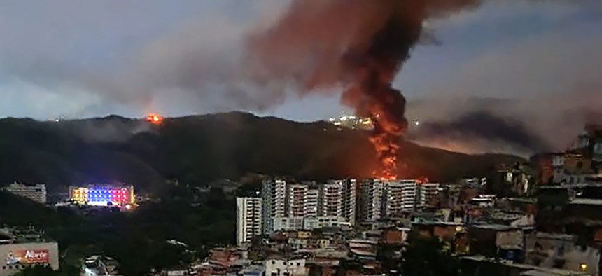 Fire at Fuerte Tiuna, Venezuela's largest military complex, is seen from a distance after a series of explosions in Caracas on January 3, 2026. 