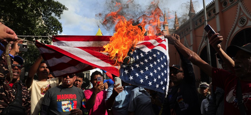 Supporters of Nicolas Maduro burn a U.S. flag during a gathering near Miraflores palace after explosions and low-flying aircraft were heard in the early hours on January 3, 2026 in Caracas, Venezuela. 