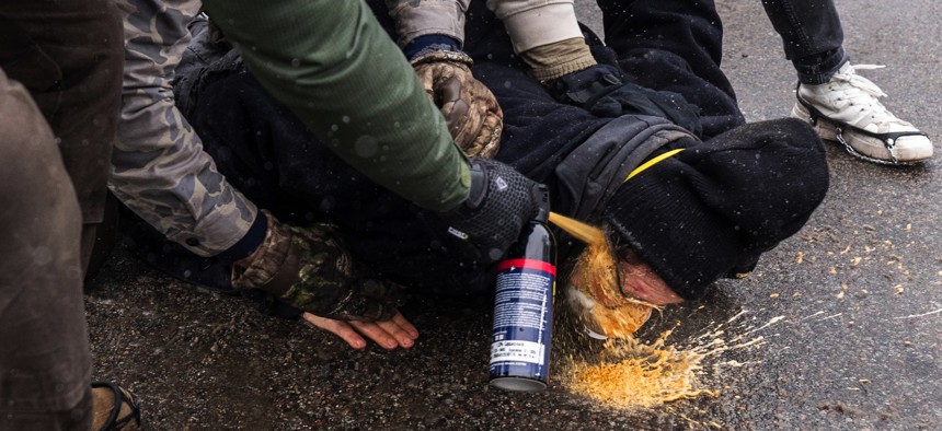 Federal agents spray a chemical irritant in the face of a protestor they pinned to the ground in south Minneapolis, Minnesota, on Jan. 21, 2026.