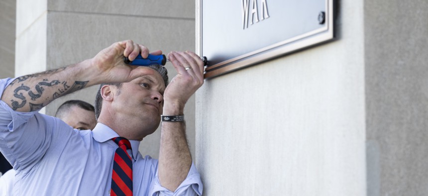 Defense Secretary Pete Hegseth finishes the installation of a "War Department" plaque at the River Entrance in front of the Pentagon on Nov. 13, 2025