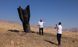 A man poses for a photo next to a fallen rocket half-buried in the ground on the outskirts of Jericho on June 8, 2026, following Iranian and Iran-backed Houthi rebel attacks.