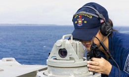 A sailor looks through an alidade as the guided-missile destroyer Milius leaves Diego Garcia on Sept. 20, 2026.
