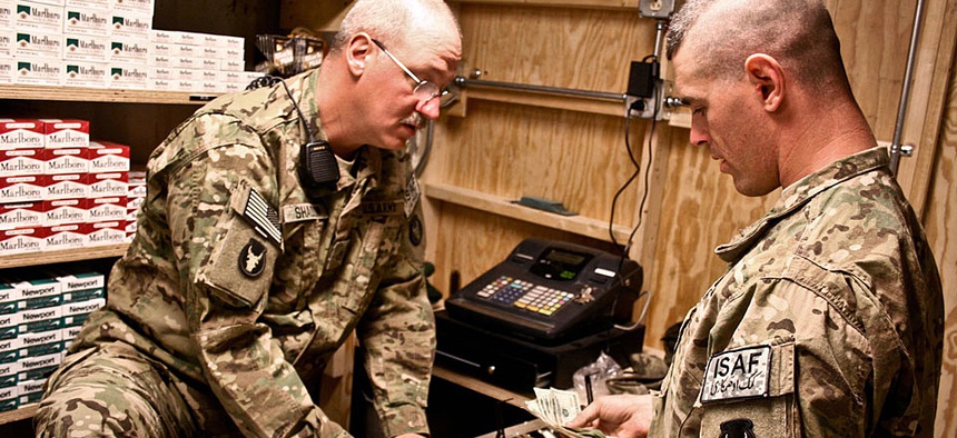 Two soldiers count sales at a new post exchange at Forward Operating Base Mehtar