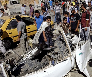 Iraqis walk around the aftermath of a car bomb attack in Sadr City, Baghdad