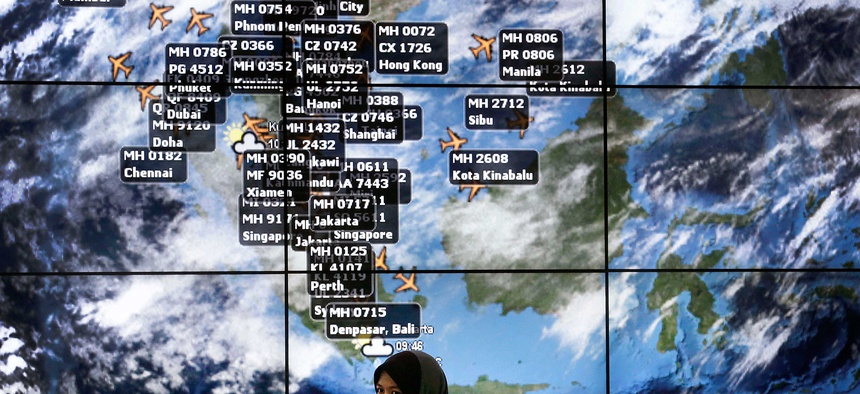 A traveller stands in front of a flight information board at Kuala Lumpur International Airport