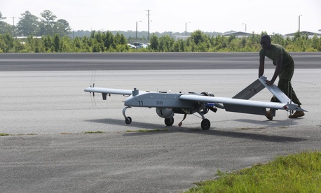 An avionics maintenance technician pushes an RQ7-B drone back to the taxiway after landing An avionics maintenance technician pushes an RQ7-B drone back to the taxiway after landing