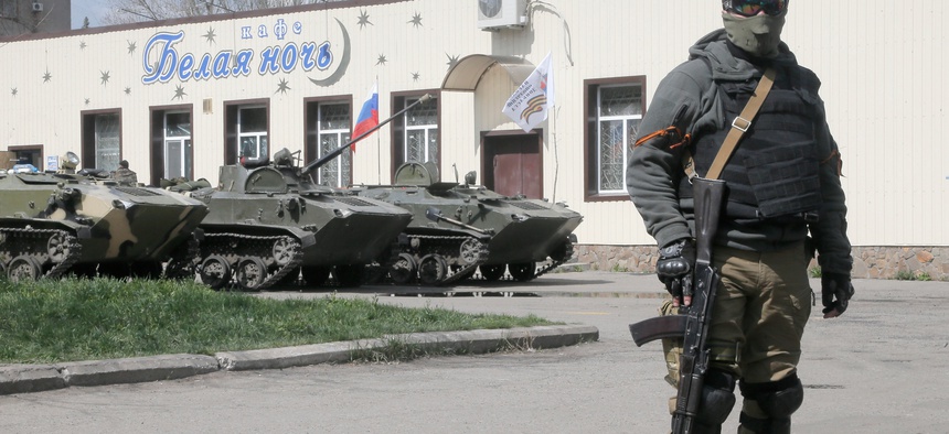A masked pro-Russian gunman guards combat vehicles in Donetsk, Ukraine