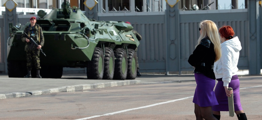 Two Ukrainian women walk past an armored personnel carrier in Kiev, Ukraine.
