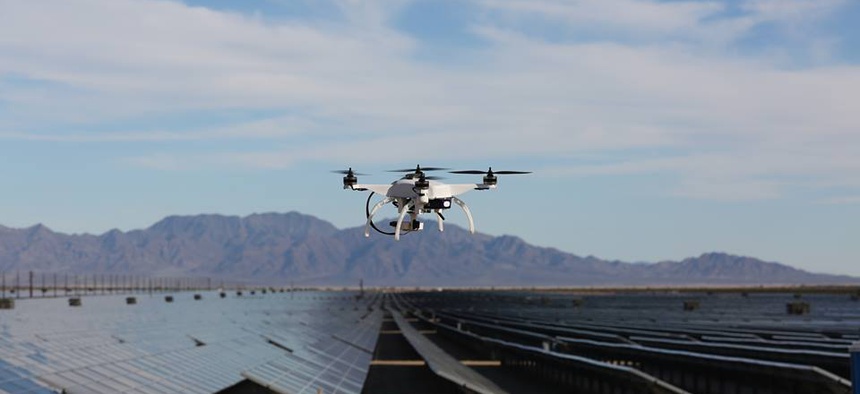 One of Skycatch's quadcopter drones hovers over a field of solar panels.