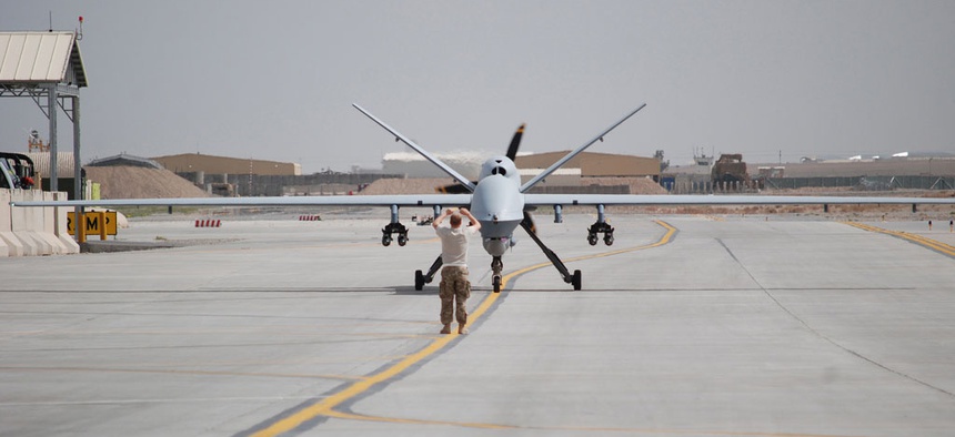 An airman with the 451st Air Expeditionary Group motions towards a MQ-9 Reaper drone taxiing at Kandahar Airfield, Afghanistan on March 20, 2014.