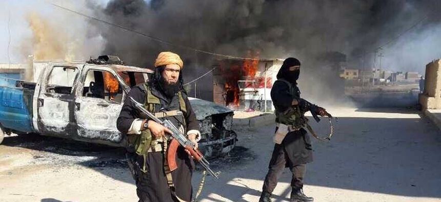 Shakir Waheib, a senior member of the al-Qaeda linked Islamic State of Iraq and the Levant, stands next to a burning police vehicle in Iraq's Anbar Province on January 4, 2014.